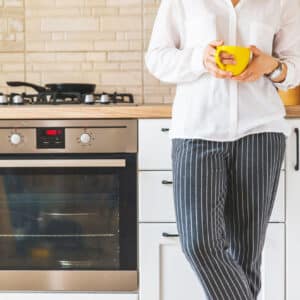 woman standing on kitchen holding yellow mug